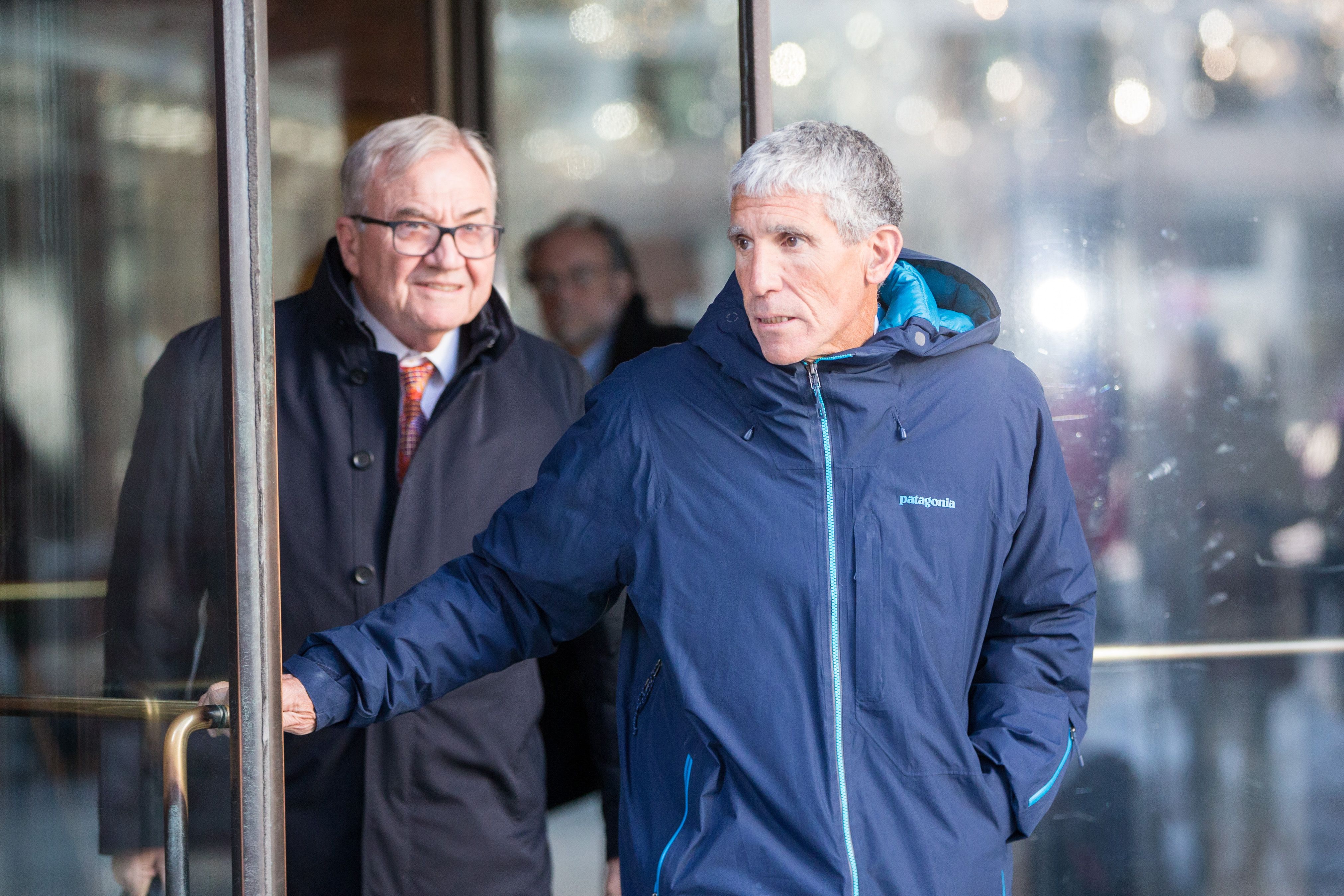 rick singer exiting a courthouse wearing a blue patagonia jacket